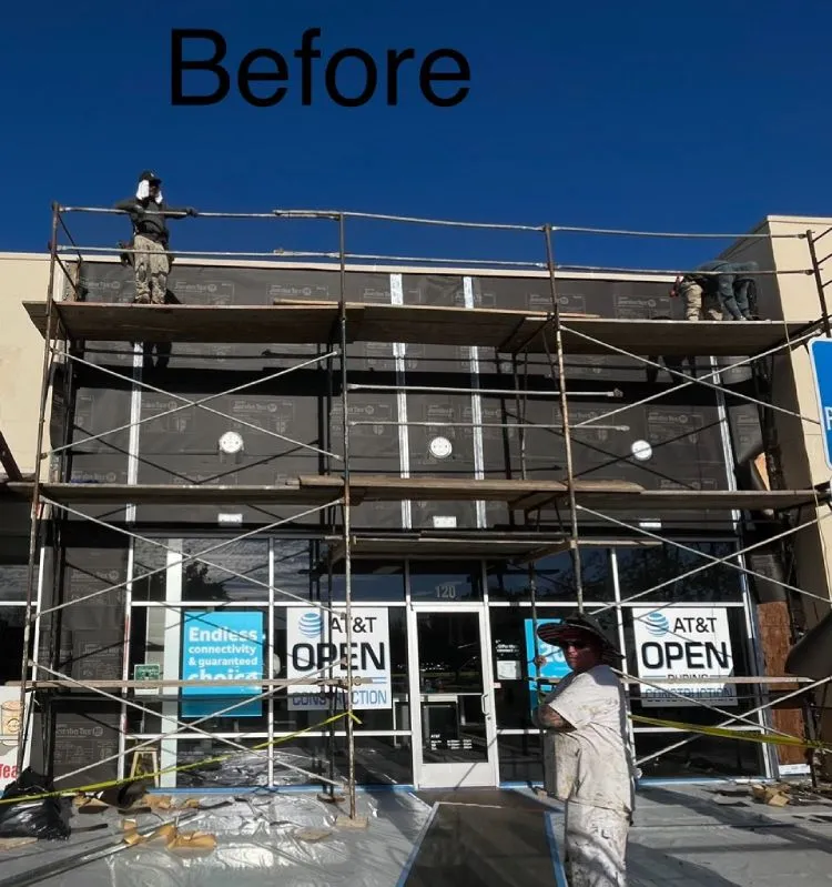 Scaffolding and weather-resistive barrier across the AT&T storefront during facade rebuild (before) — commercial stucco in the Bay Area