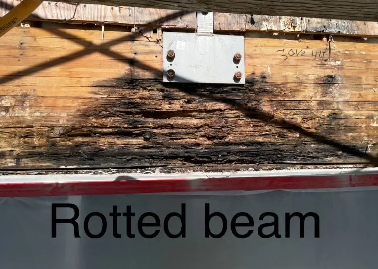 Rotted structural beam uncovered behind the failed facade — moisture damage found during inspection