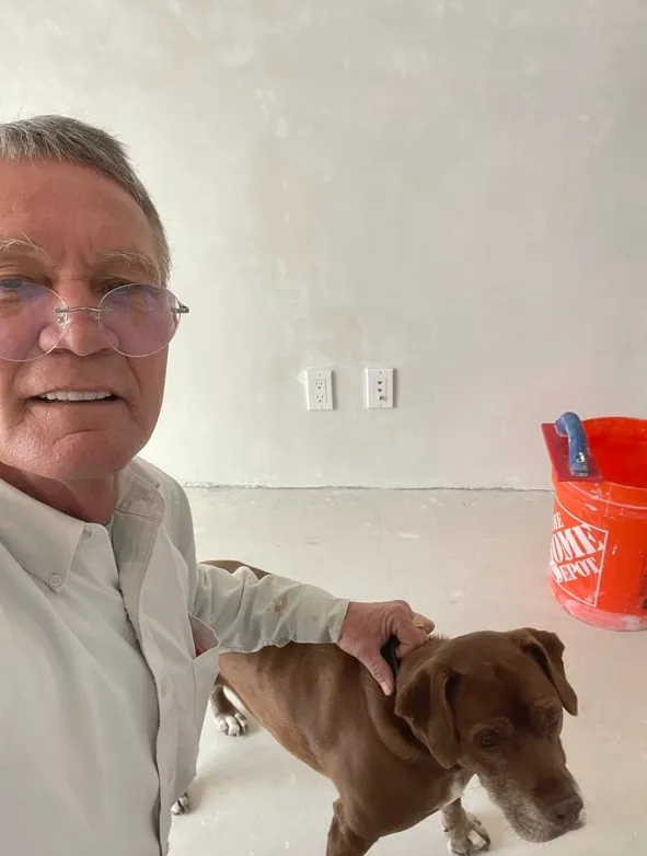 Rick Fogg, owner of Fogg Construction, on a job site with his dog in front of a freshly plastered wall