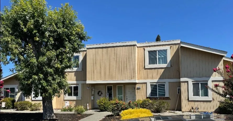 Townhome with dated vertical wood siding (before) — siding-to-stucco facade transformation
